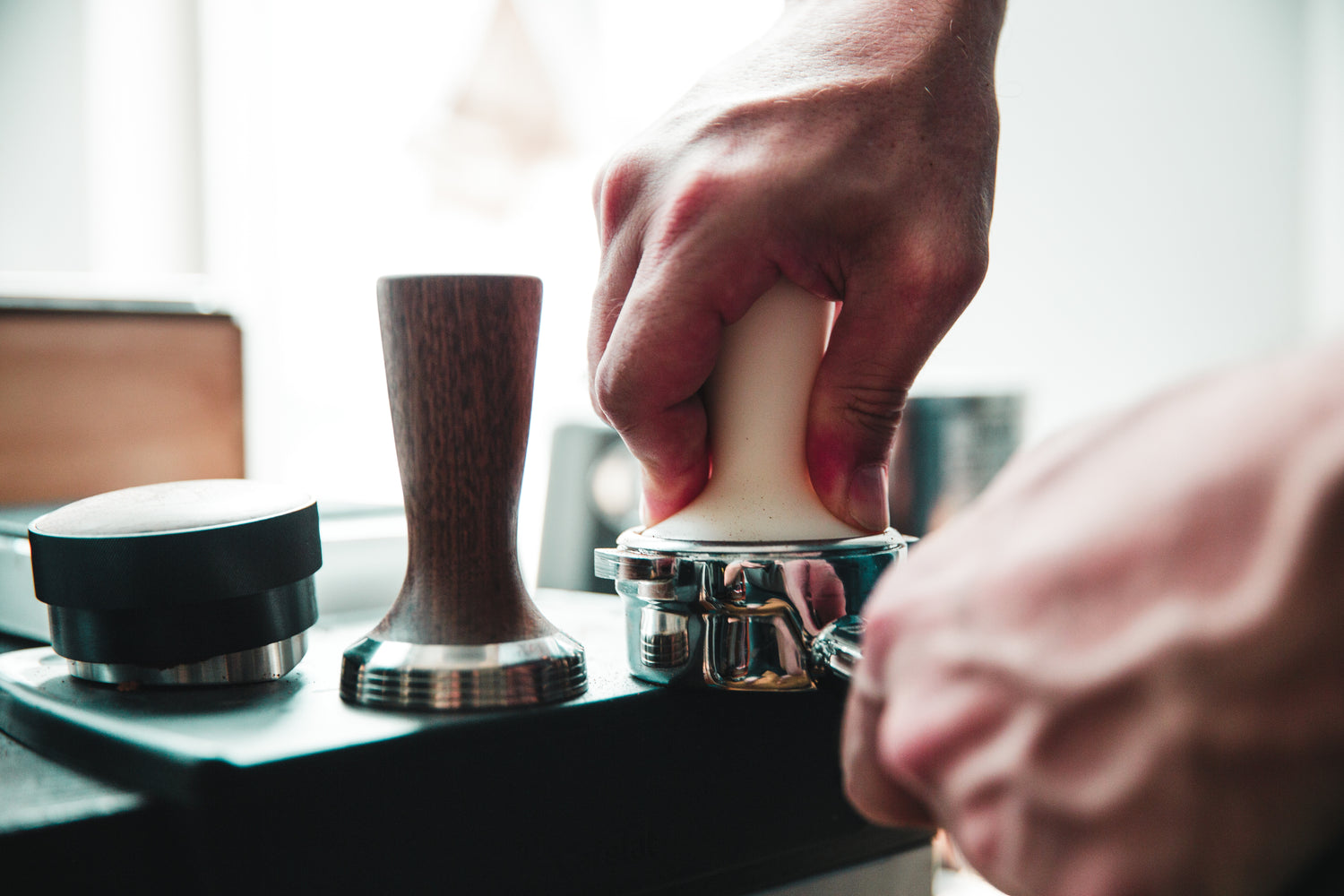 tamper being pressed into espresso machine portafilter