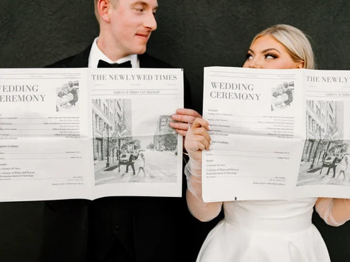 couple poses with a custom newspaper of their wedding announcement 