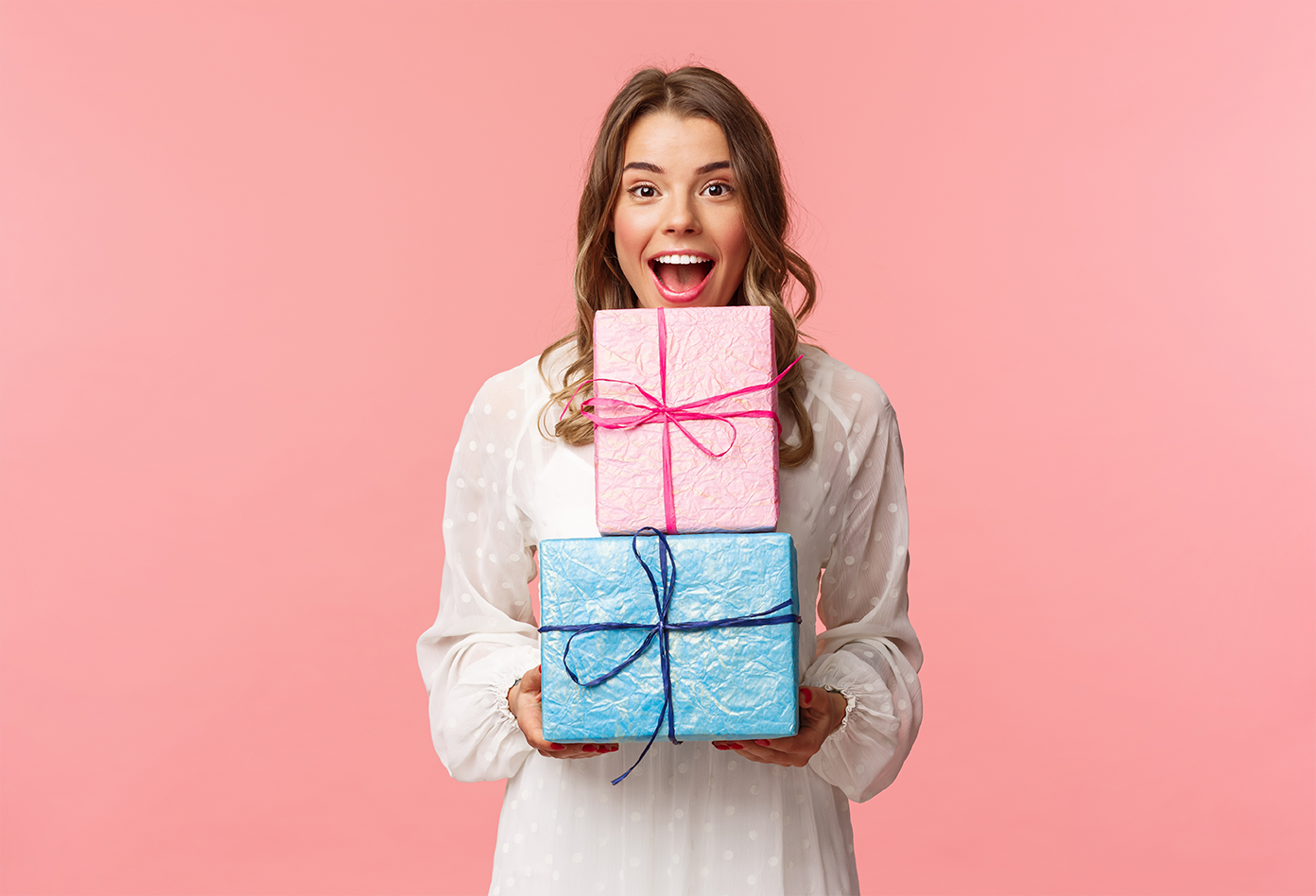 jolly and surprised woman holding two individually wrapped gifts